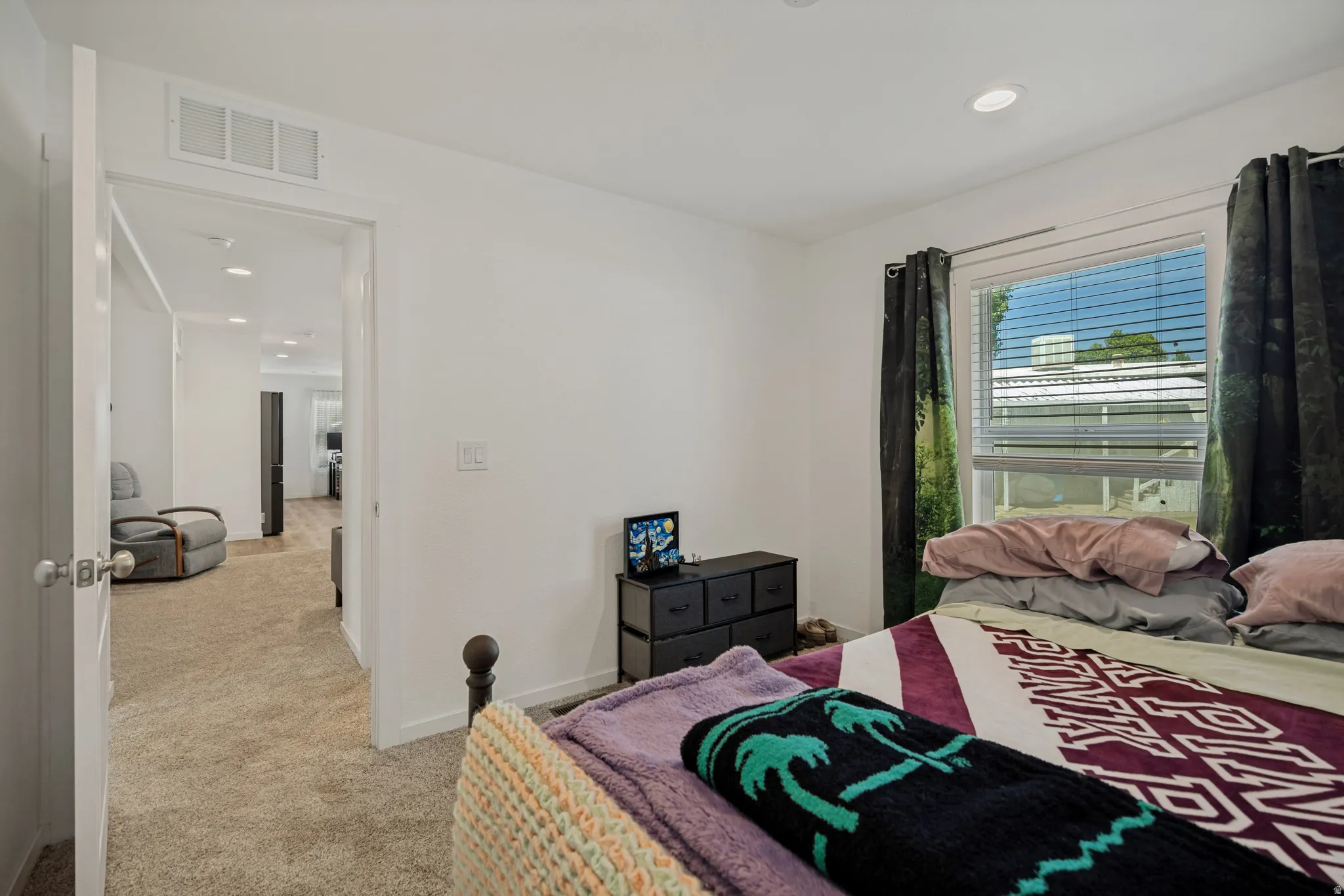 Recessed lighting, white walls, carpeted flooring, and a bedroom window with blinds