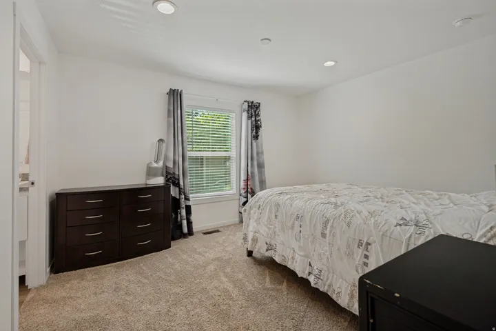 Recessed lighting illuminates the carpeted flooring and window with blinds