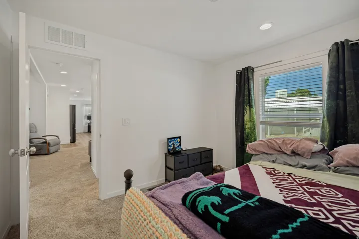 Recessed lighting, white walls, carpeted flooring, and a bedroom window with blinds