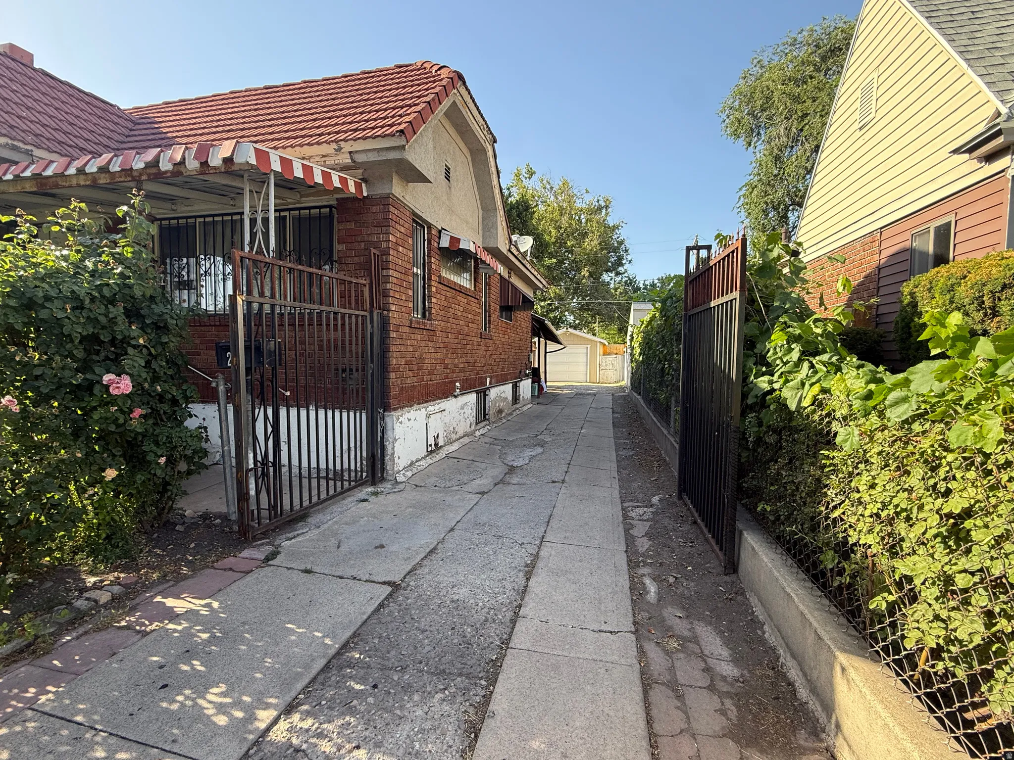 Brick exterior with a tiled roof, front porch awning, and security gates