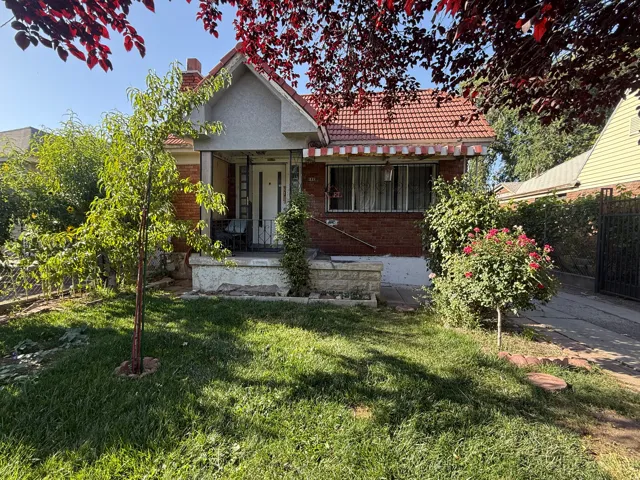 Red brick exterior with a red tile roof, covered front porch, and a patterned awning