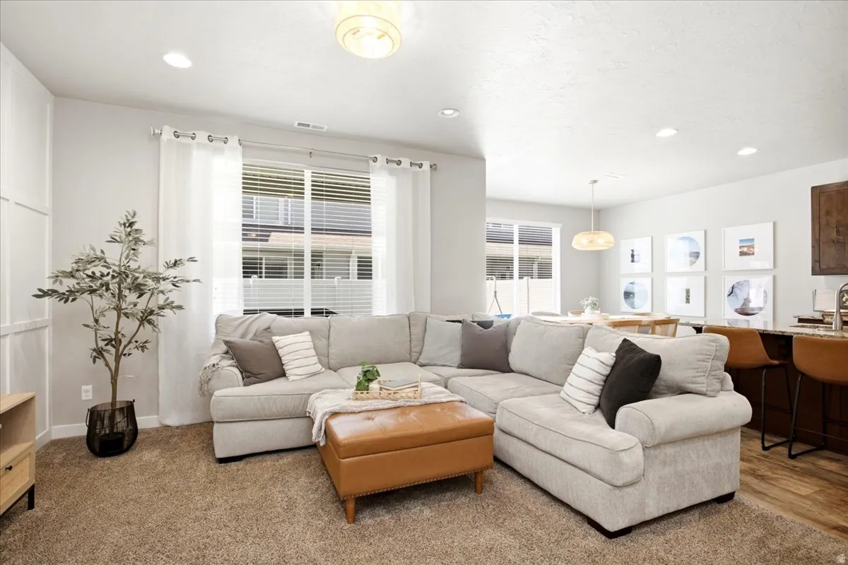 Recessed lighting, large window with blinds, paneling detail on walls, wood-finish flooring, and pendant lighting