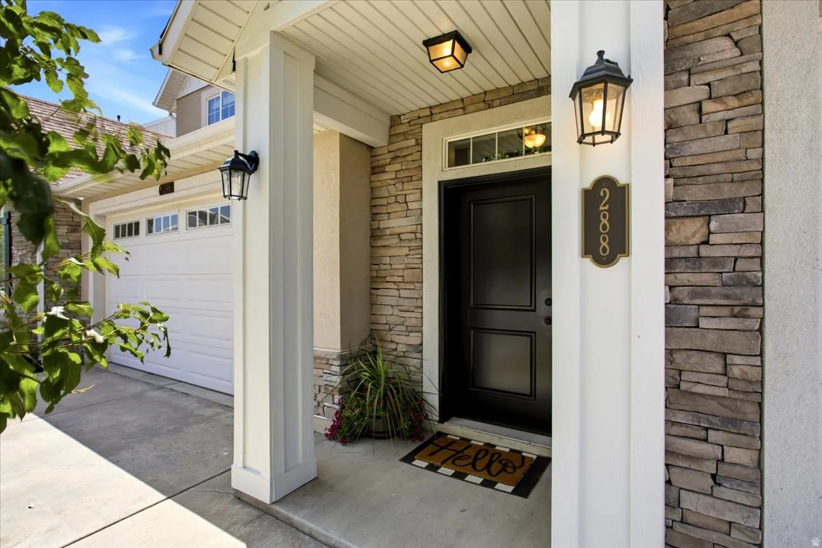 Entryway featuring stone facade, a black panel door with transom window, and exterior lighting fixtures