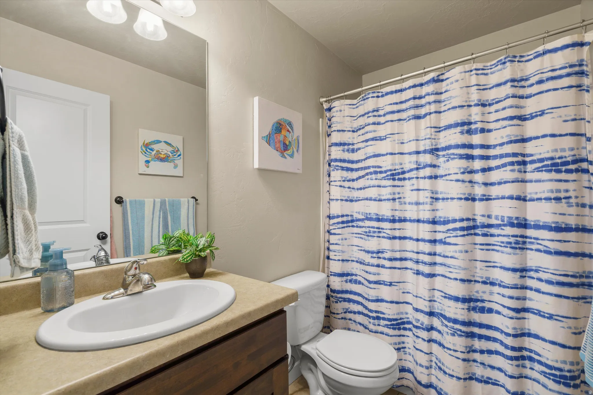 Vanity with a single basin sink, a wall-mounted mirror, and overhead lighting