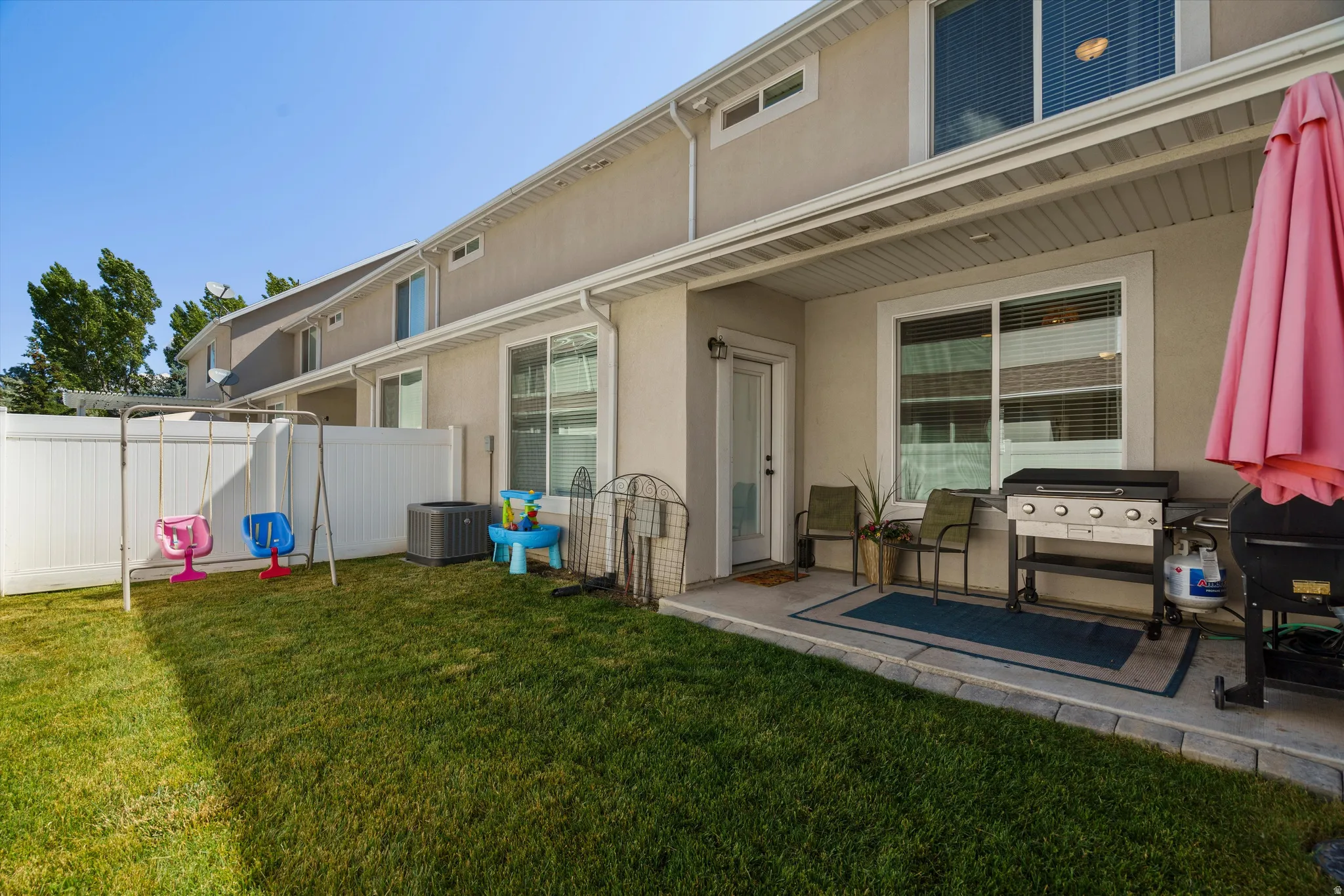 Private backyard with a fenced perimeter, concrete patio, and mature lawn