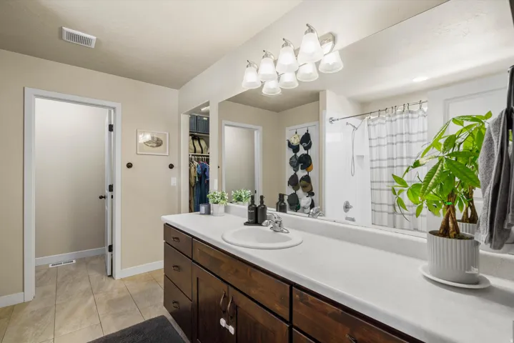 Spacious vanity with a white countertop and dark wood-finish cabinetry, featuring an integrated sink