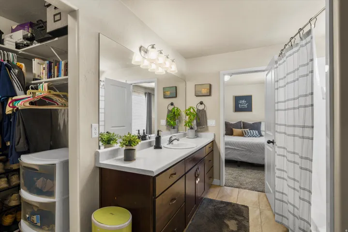 Bathroom featuring a dual sink vanity with integrated sinks, a wall-mounted light fixture, and a mirror