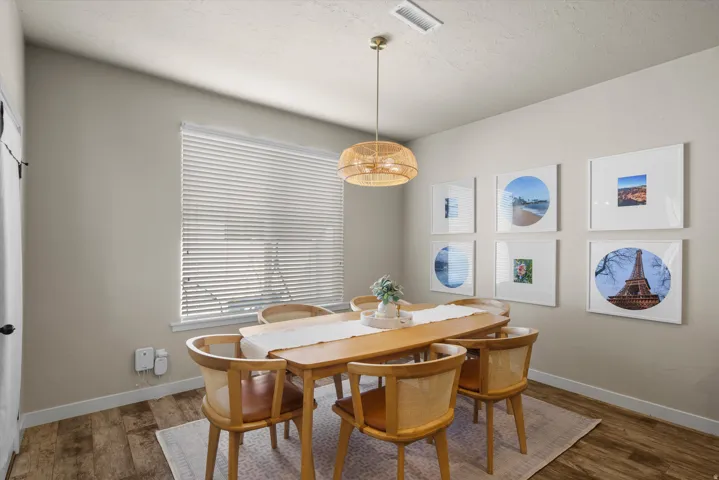 Dining area featuring wood-finish flooring, a contemporary overhead lighting fixture, and a single window with blinds
