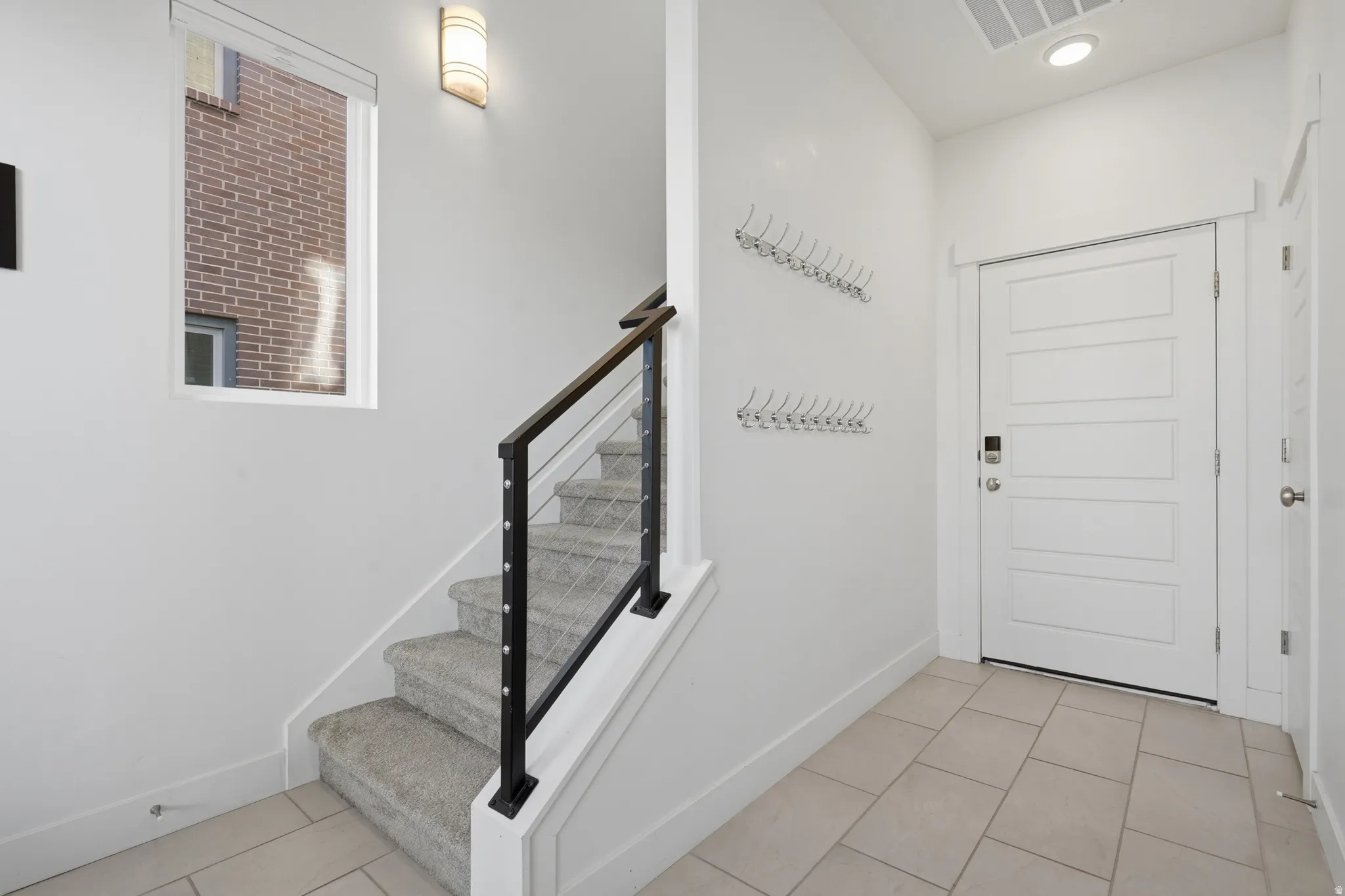 Tiled entry flooring, paneled entry door, carpeted staircase, and contemporary stair railing