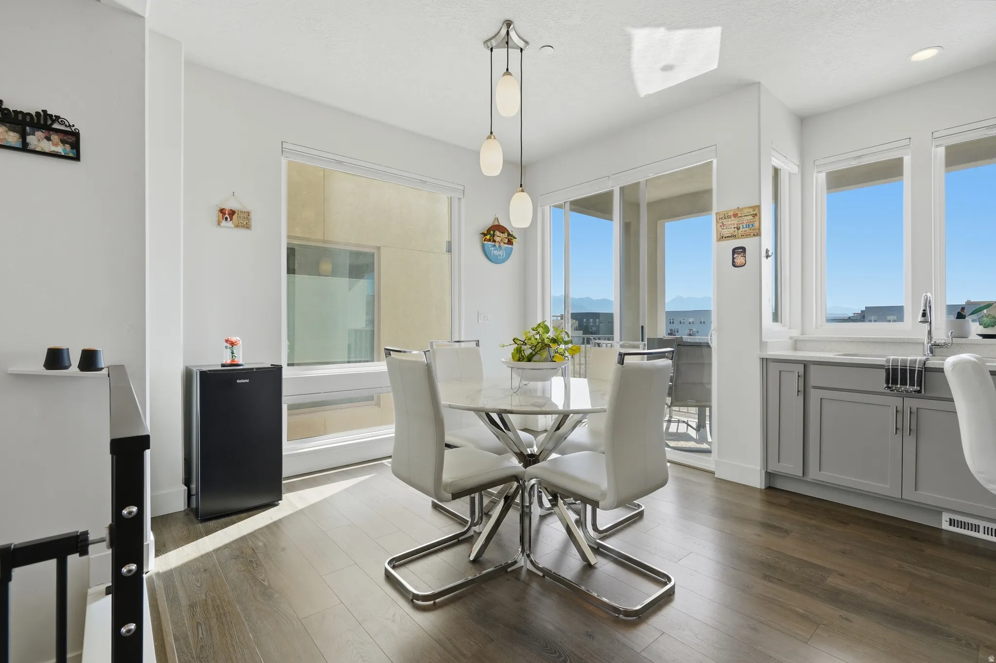 Wood-finish flooring, white walls, kitchen sink, gray cabinetry, and a sliding glass door