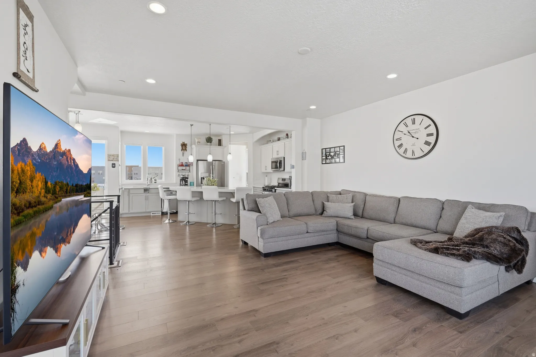 Open-concept living space featuring wood-finish flooring, recessed lighting, and a kitchen with a large island and pendant lighting