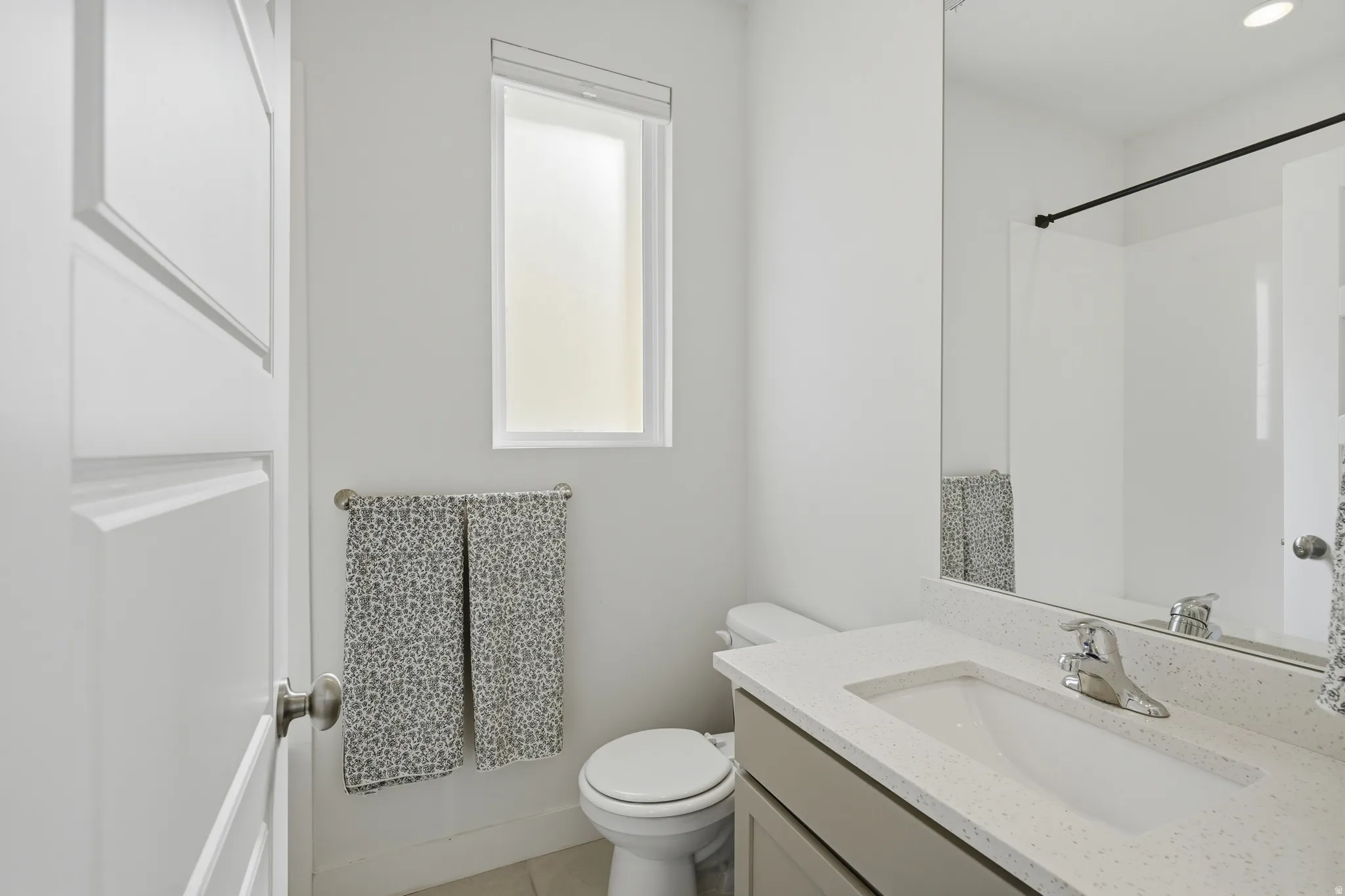 Modern bathroom featuring a single vanity with stone-finish countertop, undermount sink, and chrome faucet
