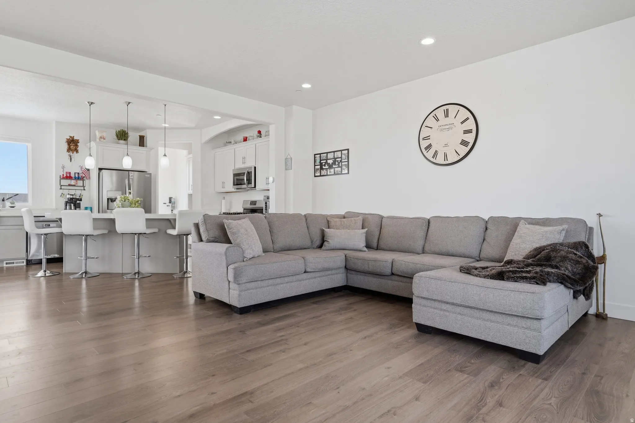 Open-concept living space featuring wood-finish flooring, recessed lighting, and a kitchen with a breakfast bar