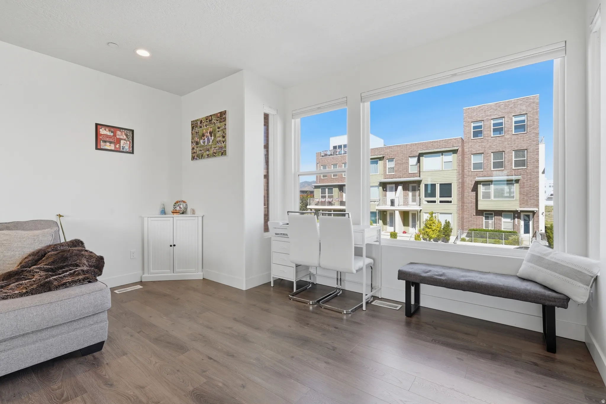 Expansive windows, wood-finish flooring, recessed lighting, and a built-in corner cabinet