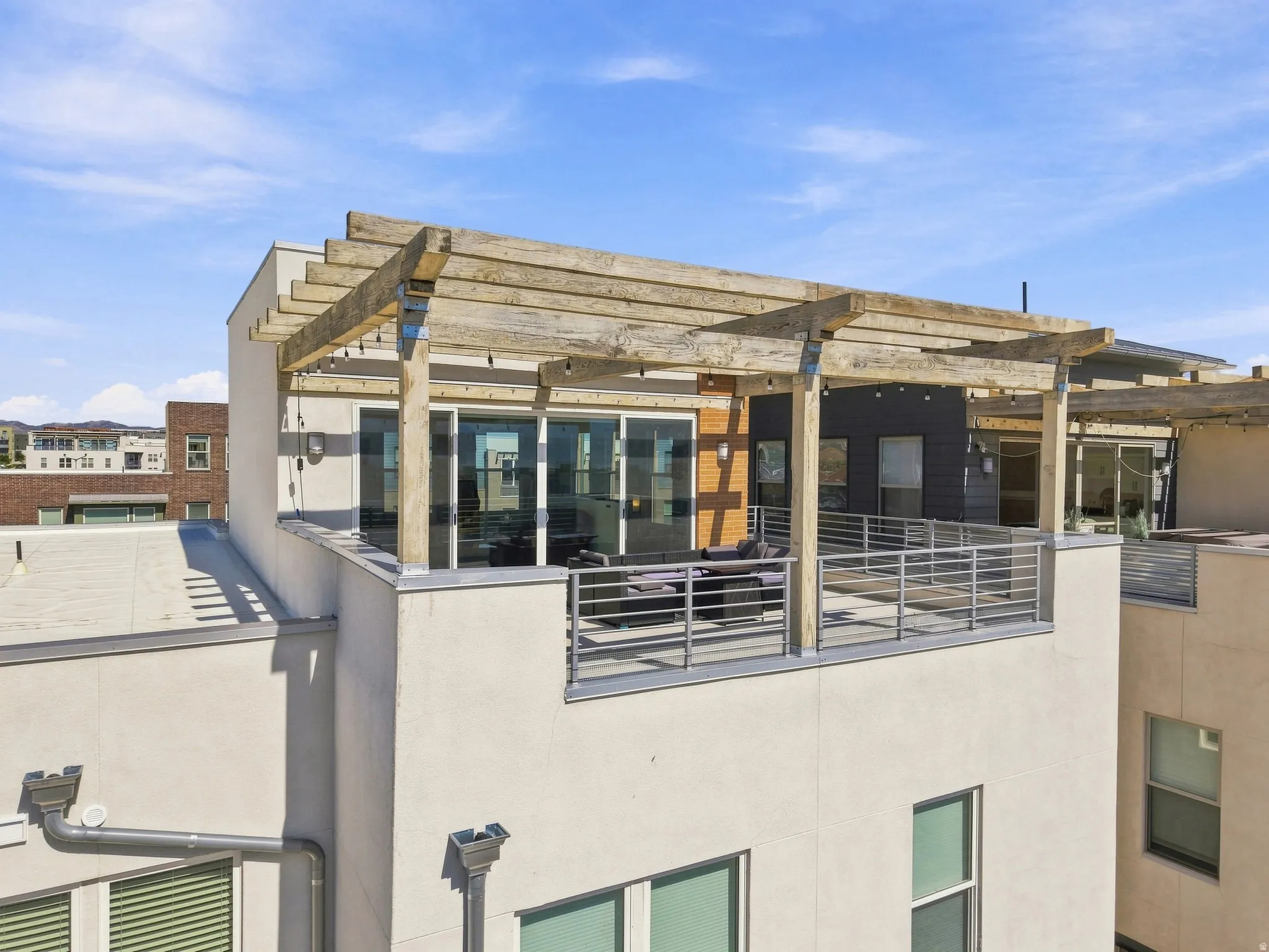 Rooftop deck featuring a wooden pergola, sliding glass doors, and metal railings