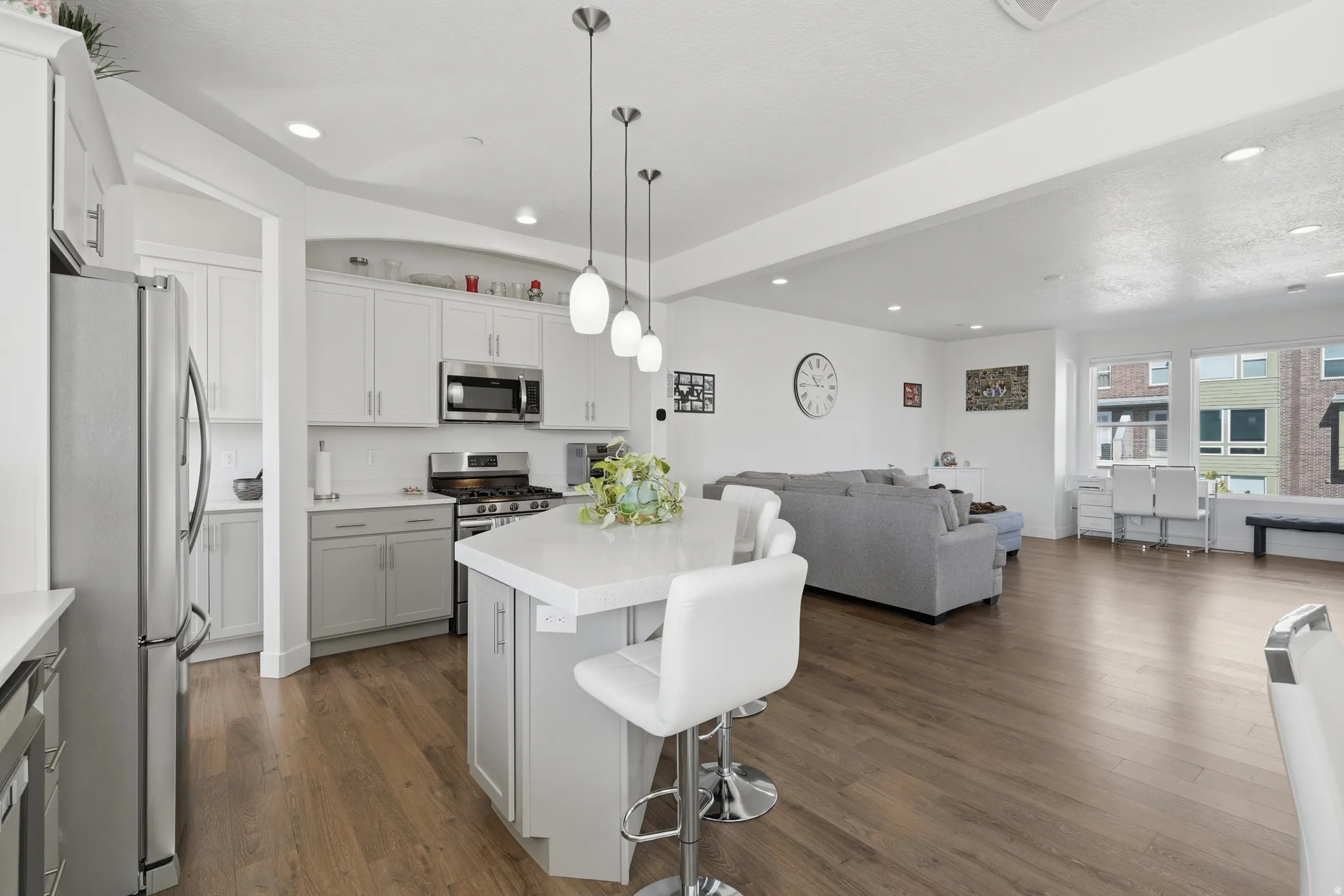 Open-concept living space with wood-finish flooring, recessed lighting, and large windows