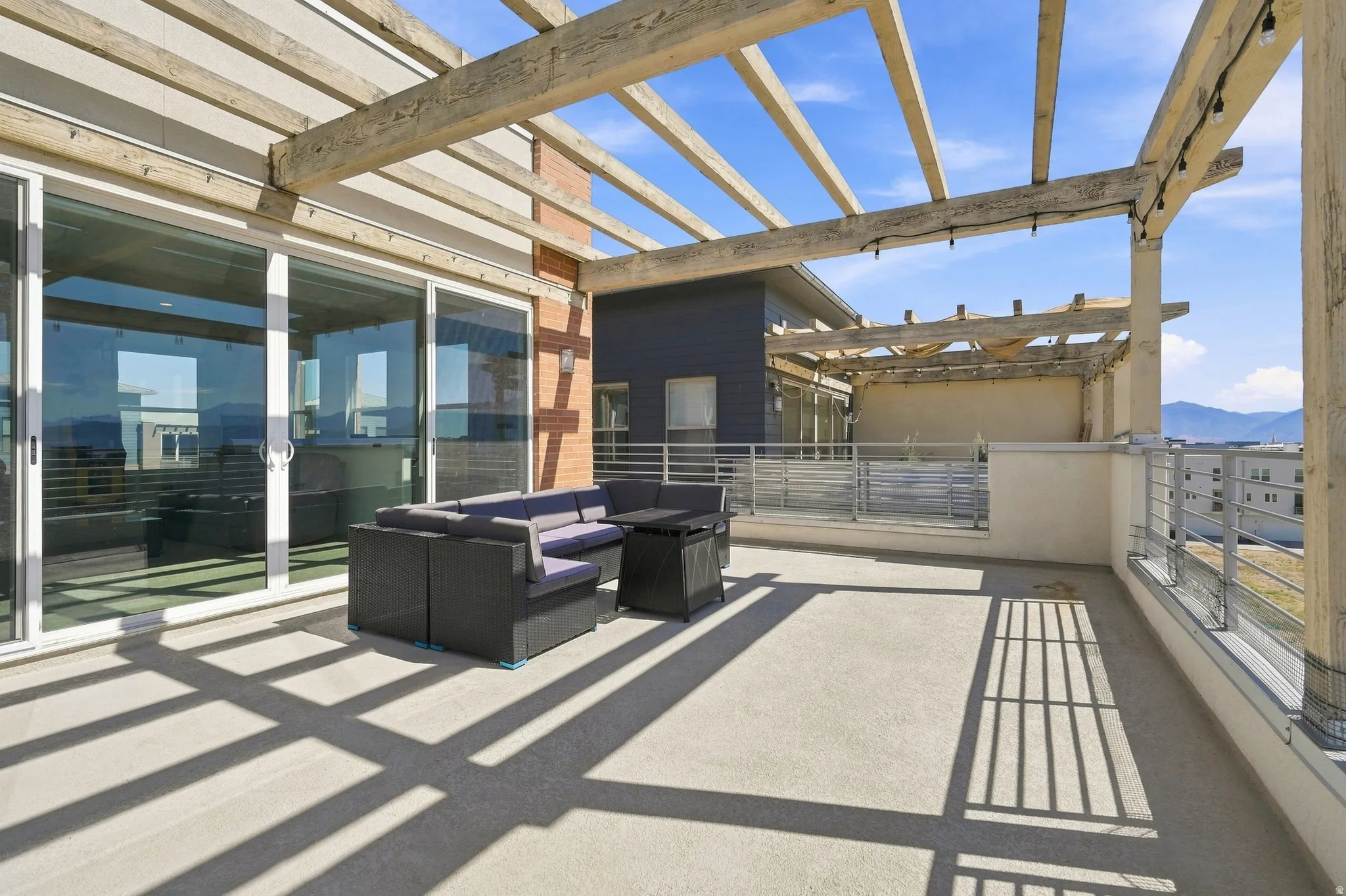 Spacious outdoor patio featuring a wooden pergola, sliding glass doors, and metal railings