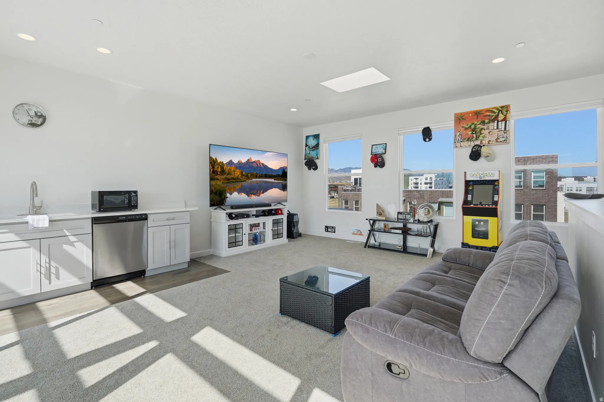 Open-concept living area featuring a wet bar with stainless steel appliances, a skylight, recessed lighting, and multiple windows