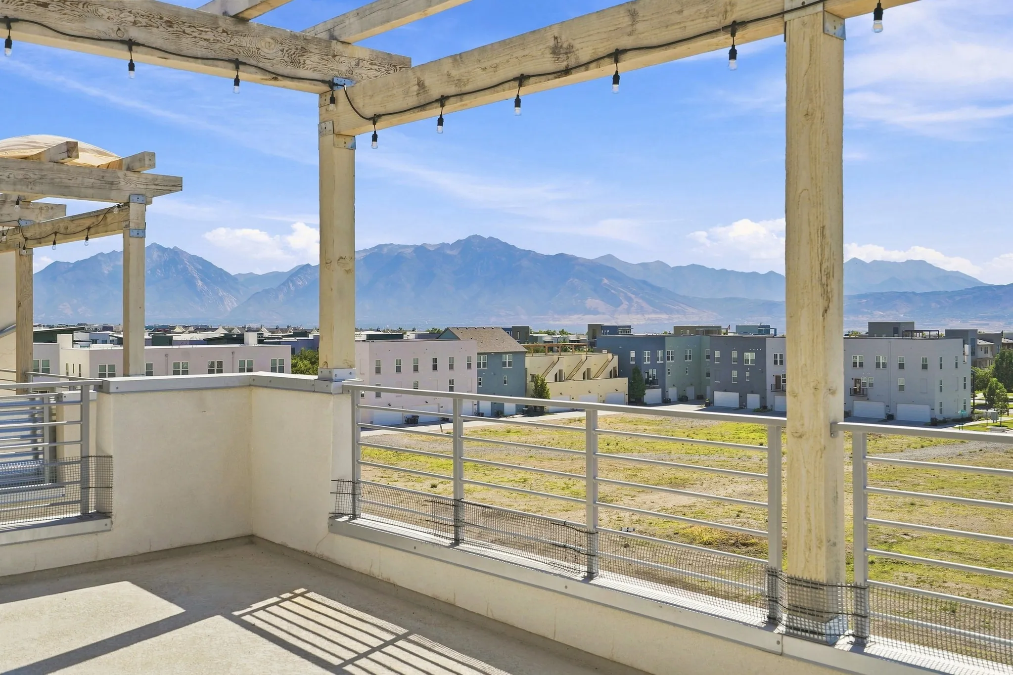Rooftop deck featuring a wood pergola and string lighting