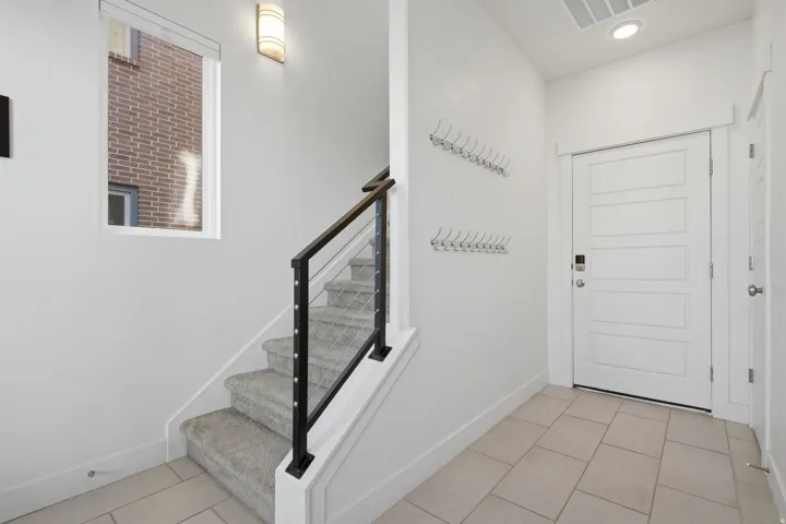 Tiled entry flooring, paneled entry door, carpeted staircase, and contemporary stair railing