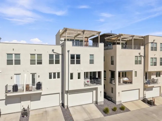Contemporary townhome exterior with multiple balconies, private garages, and rooftop pergolas