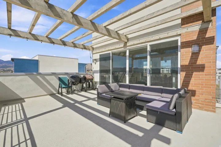 Rooftop patio with a wood pergola, concrete decking, and brick exterior wall