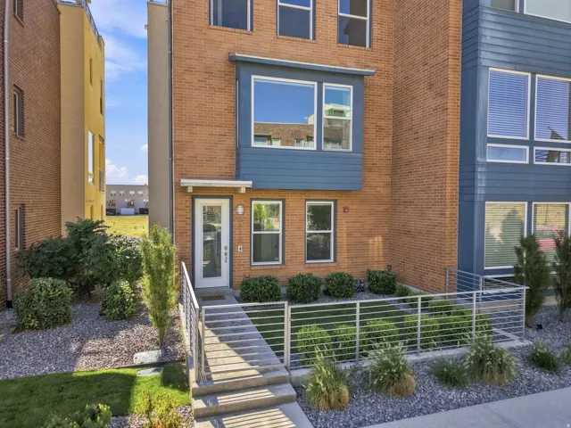 Brick exterior with blue paneling, multiple windows, metal railings, and landscaping