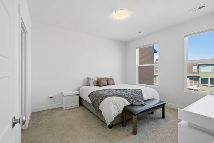 Carpeted bedroom featuring white walls, two large windows, and a flush-mount ceiling light fixture