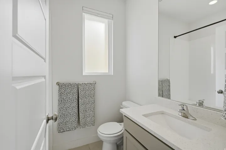 Modern bathroom featuring a single vanity with stone-finish countertop, undermount sink, and chrome faucet