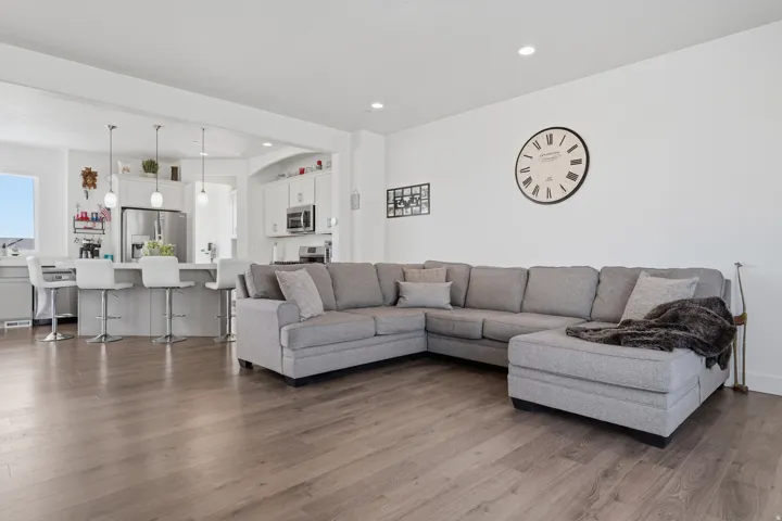 Open-concept living space featuring wood-finish flooring, recessed lighting, and a kitchen with a breakfast bar