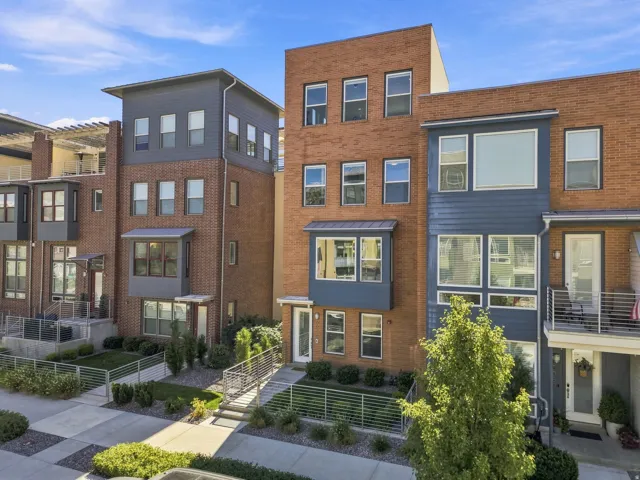 Contemporary townhome featuring a brick and horizontal siding facade, multiple large windows, a bay window, and a private balcony