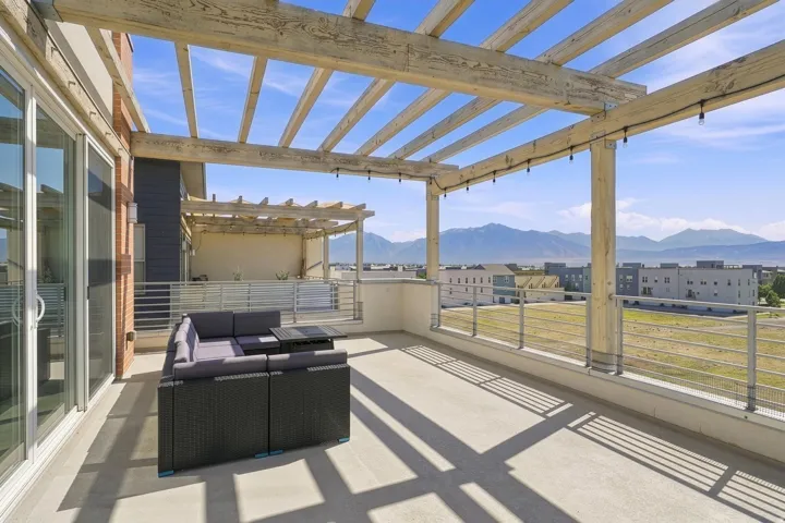 Rooftop deck with a wood pergola, mountain backdrop, concrete flooring, and sliding glass doors