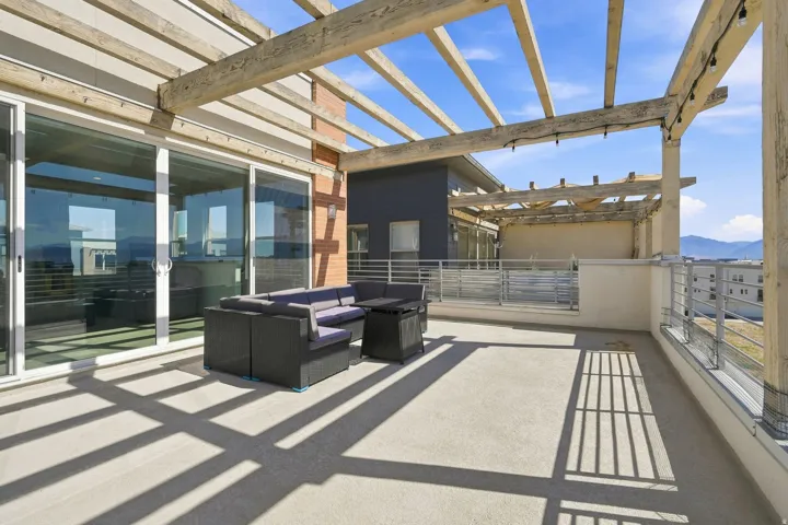 Spacious outdoor patio featuring a wooden pergola, sliding glass doors, and metal railings