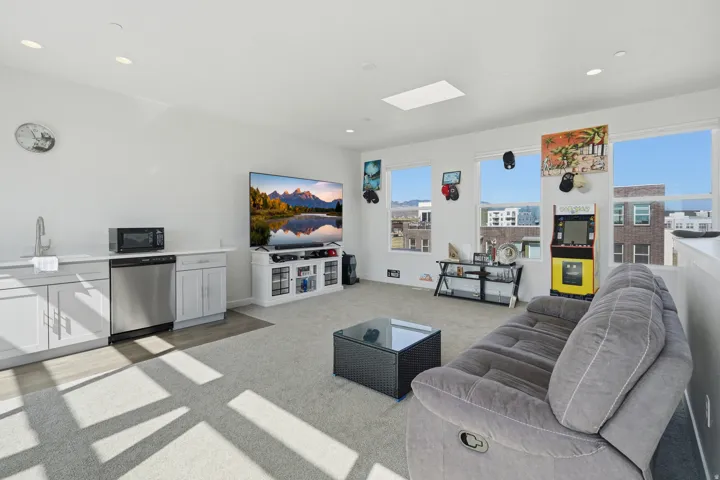 Open-concept living area featuring a wet bar with stainless steel appliances, a skylight, recessed lighting, and multiple windows