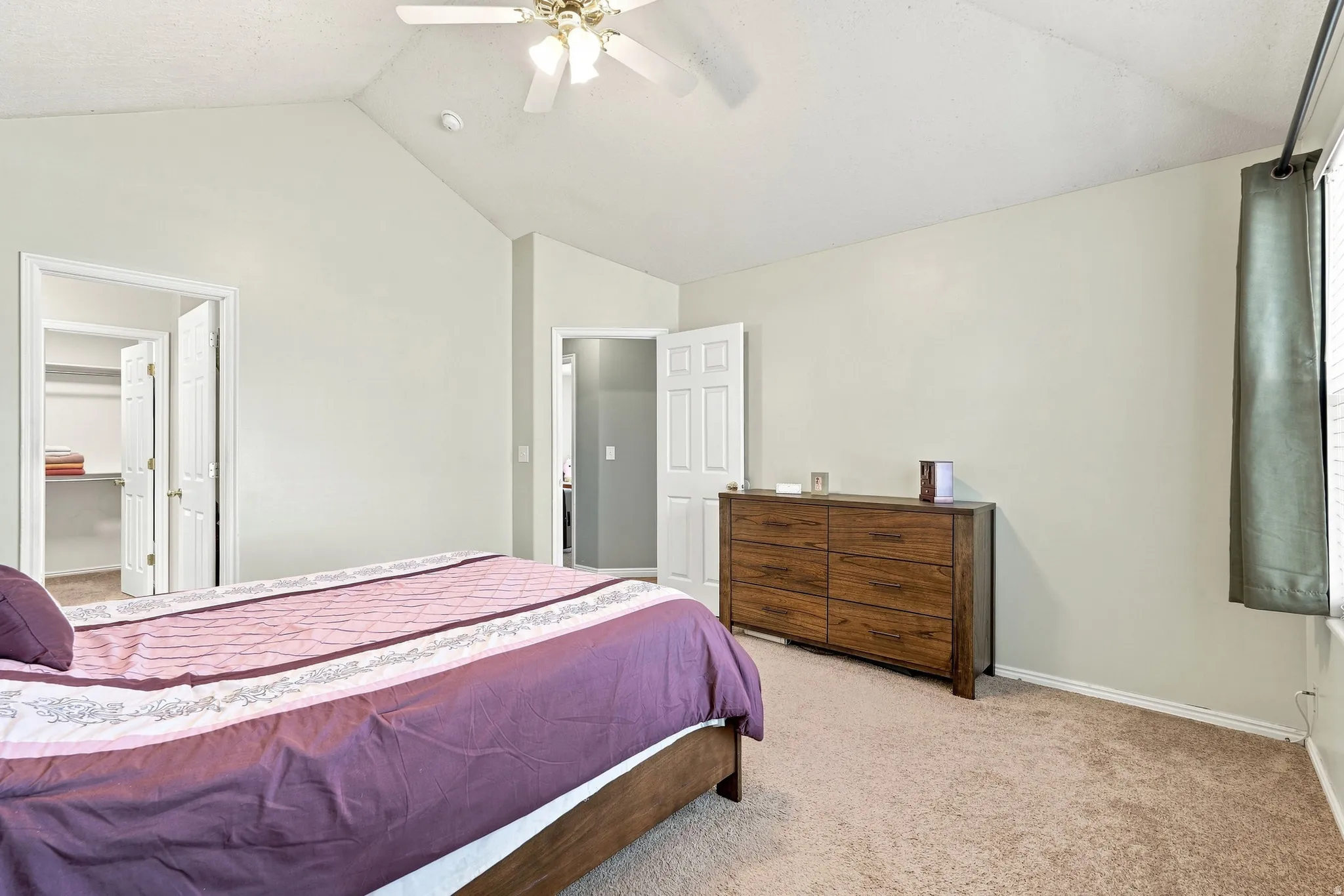 Vaulted ceiling with a ceiling fan, carpeted flooring, and a built-in closet with bi-fold doors