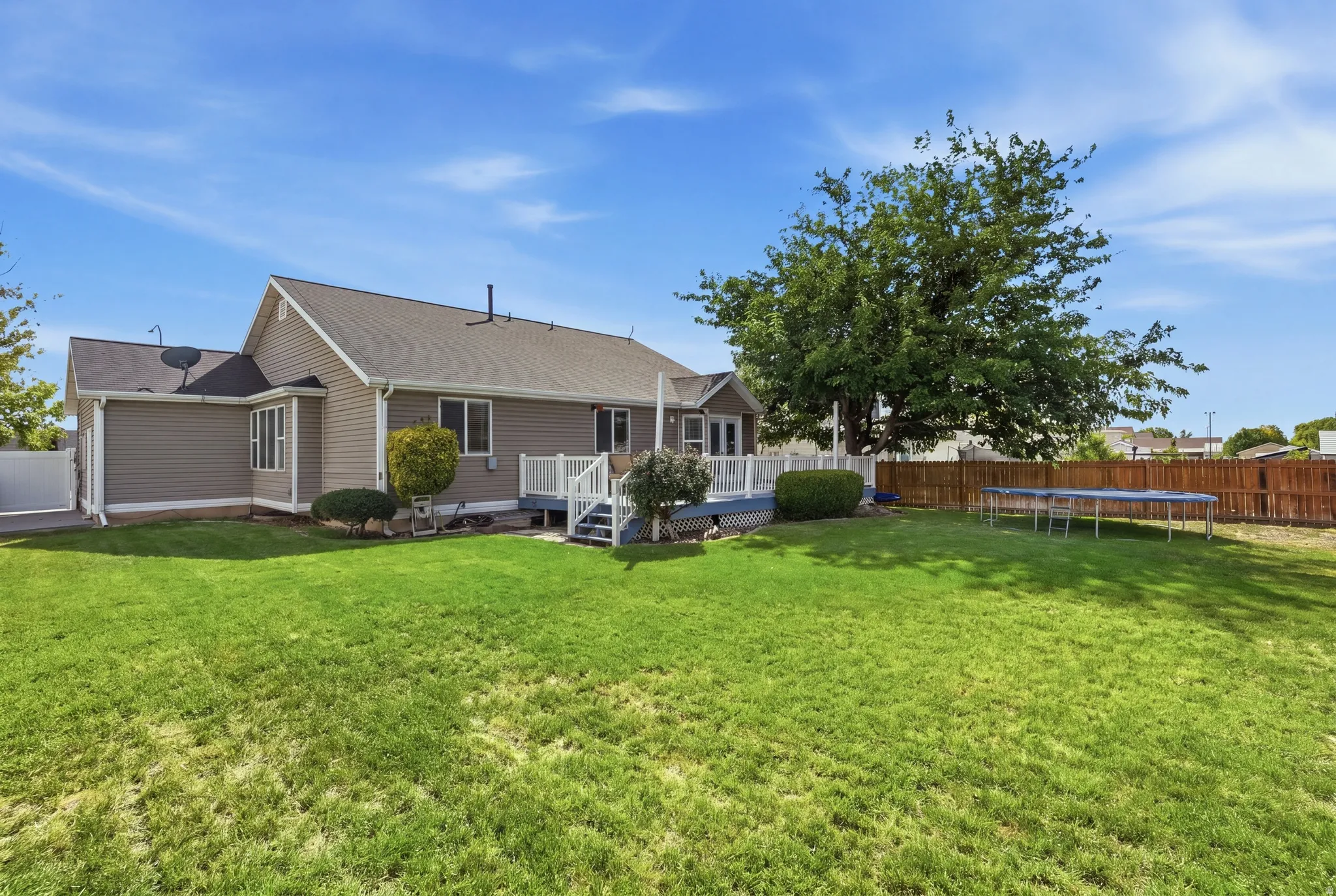 Spacious backyard featuring a manicured lawn, a large deck with railings, and a wood privacy fence