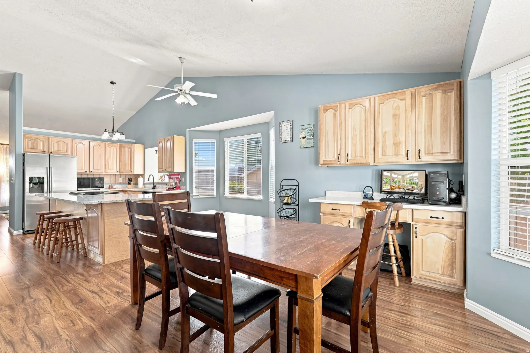 Spacious kitchen with wood-finish flooring, light wood cabinetry, stainless steel appliances, and a central island with a countertop