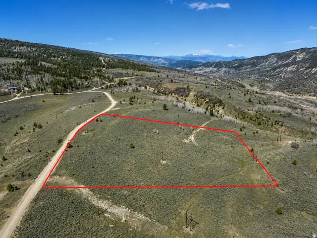 Expansive undeveloped lot with natural ground cover, bordered by a dirt road