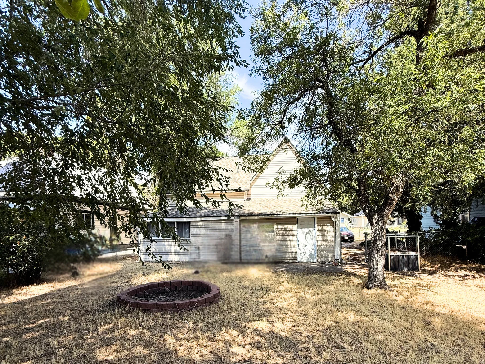 Expansive backyard featuring mature trees and a built-in fire pit