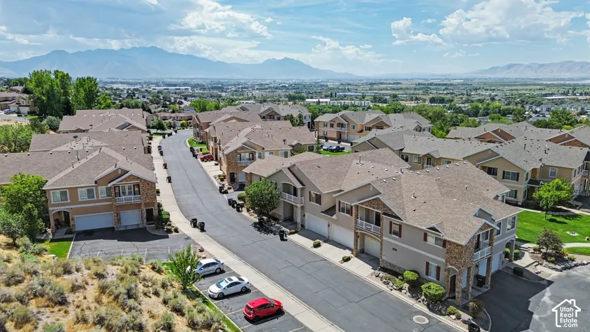 Community of multi-level residences with stone accents, attached garages, and a paved street