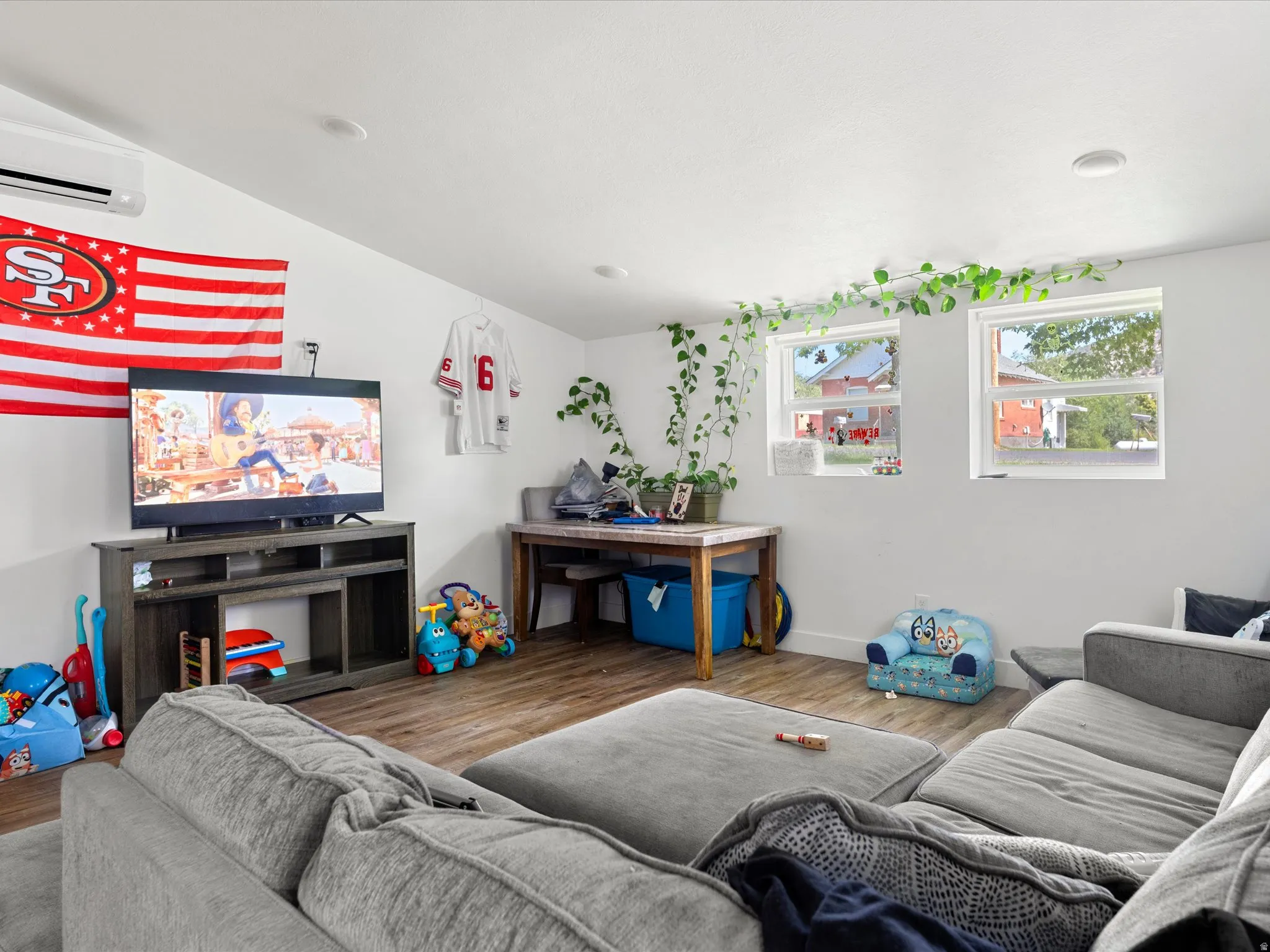 White walls, wood-finish flooring, two windows, recessed lighting, and a wall-mounted AC unit