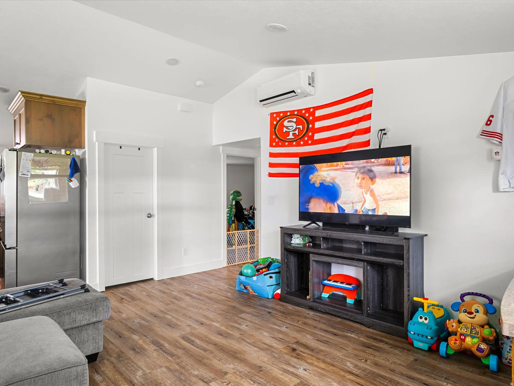 Wood-finish flooring, white walls, and a vaulted ceiling