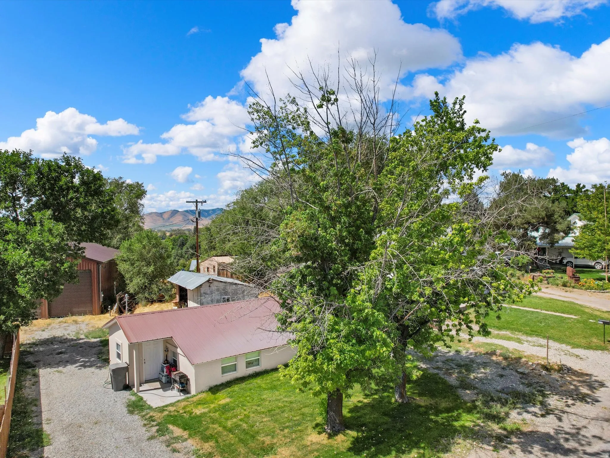 Single-story residence with a metal roof, gravel driveway, and a grassy yard