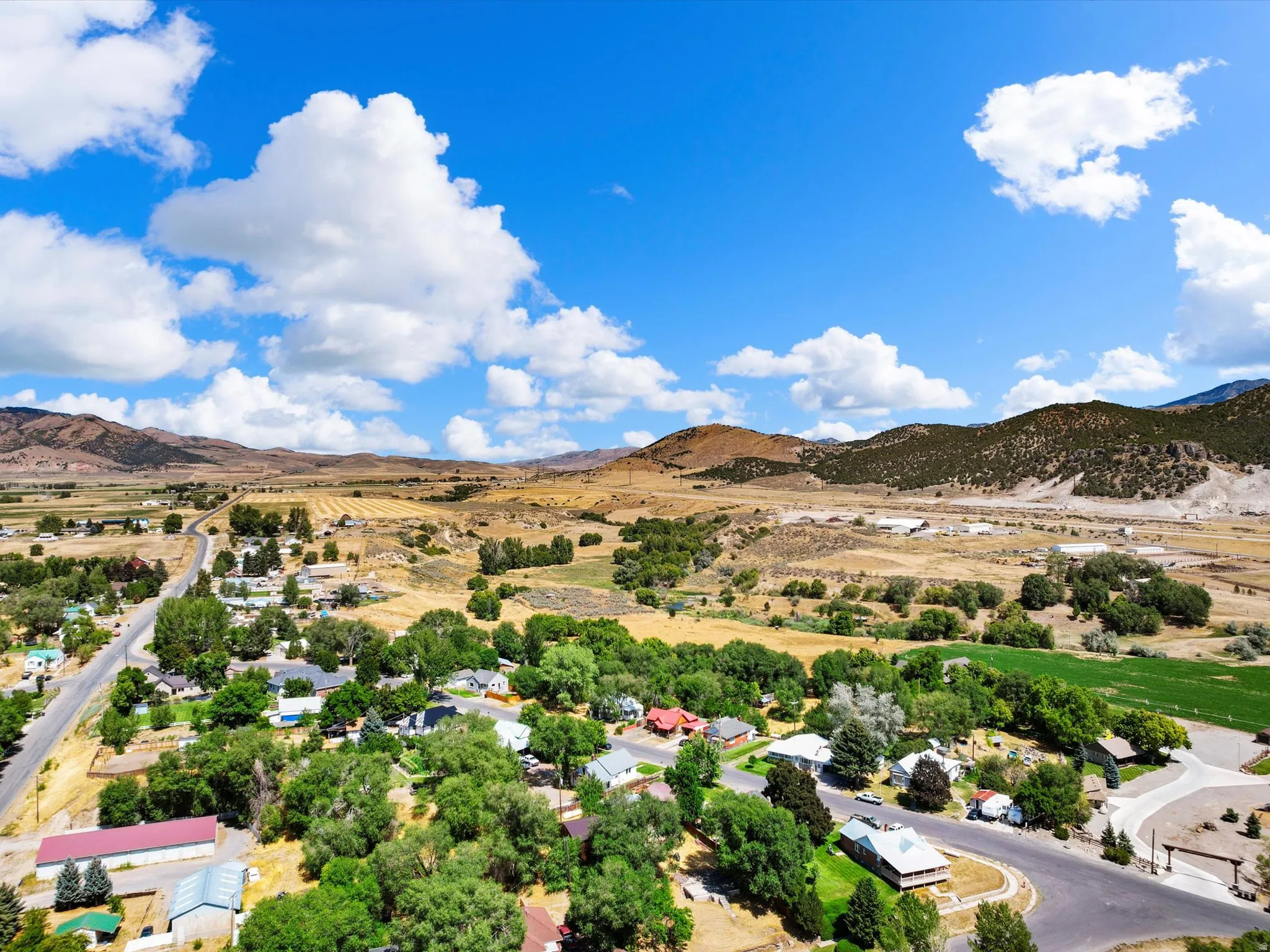 Expansive rural landscape featuring a residential community, surrounding agricultural fields, and distant mountainous terrain