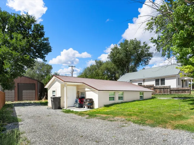 Exterior featuring a metal roof, gravel driveway, and a separate structure with a roll-up door