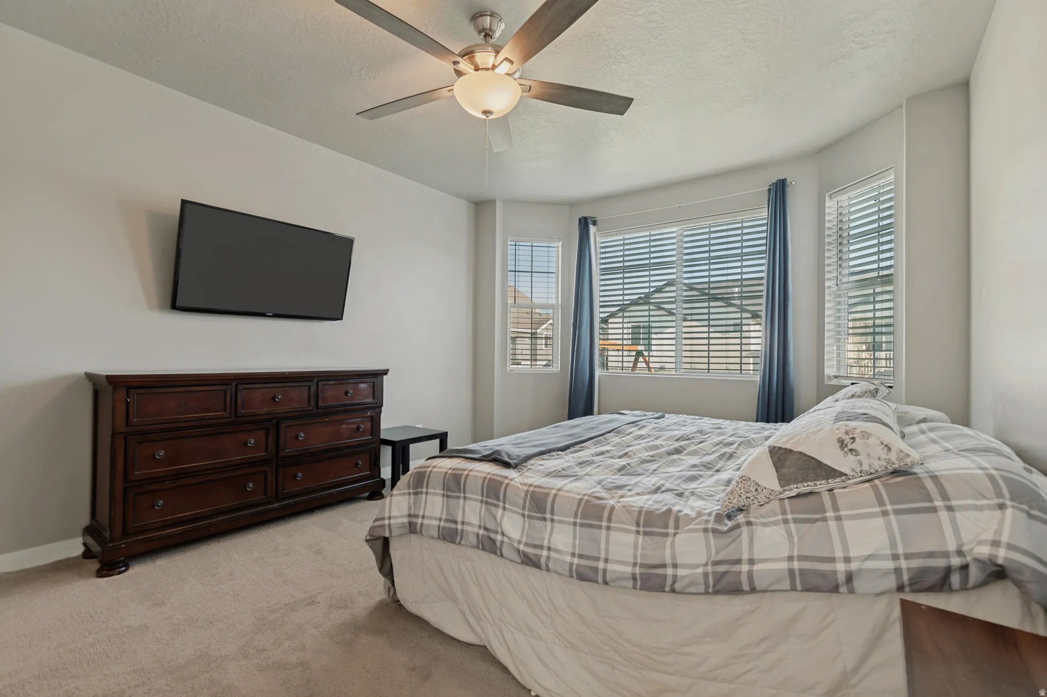 Recessed bay window, ceiling fan, neutral wall tones, window blinds, and carpeting