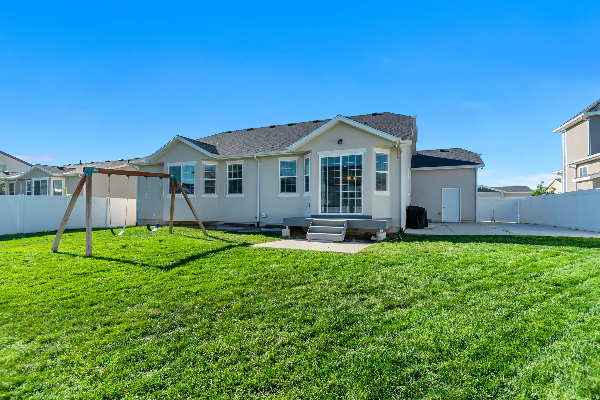 Expansive rear yard featuring a manicured lawn, full privacy fencing, and a built-in patio