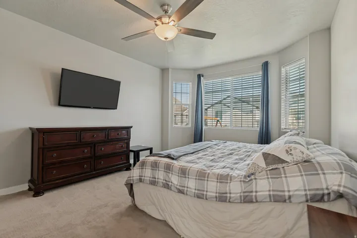 Recessed bay window, ceiling fan, neutral wall tones, window blinds, and carpeting