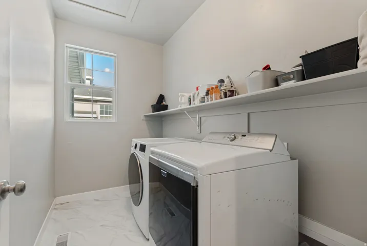 Laundry area with a window, wall-mounted shelving, and tile flooring
