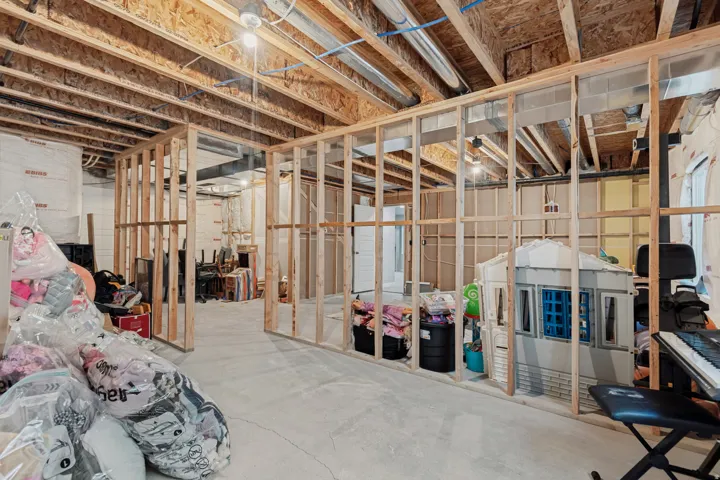 Unfinished basement with concrete flooring, exposed wood framing, and exposed ceiling joists